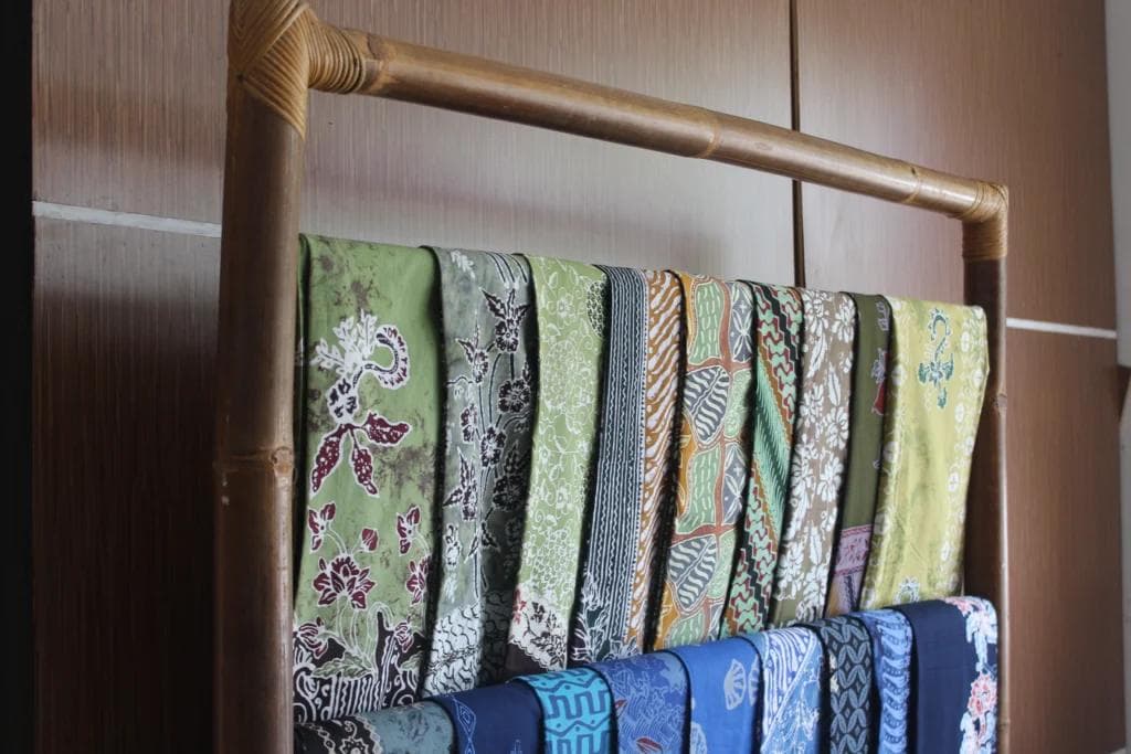 Batik fabrics displayed on a bamboo rack