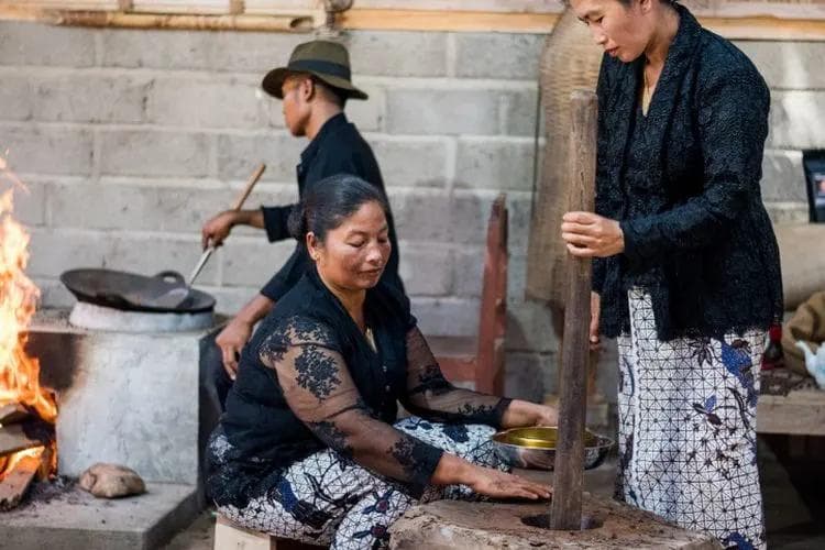 Three people from the Osing tribe are processing coffee using a traditional method.