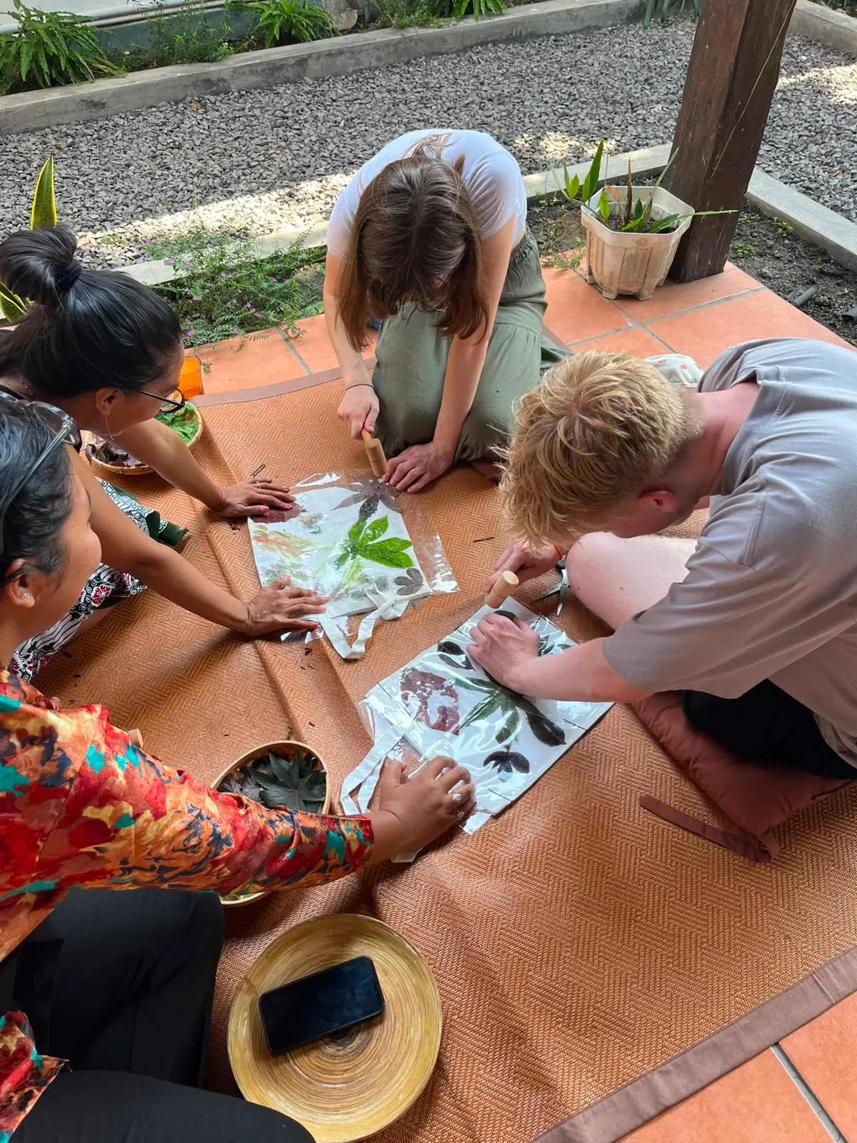 Workshop participant pounding leaves onto fabric using the eco print pounding technique