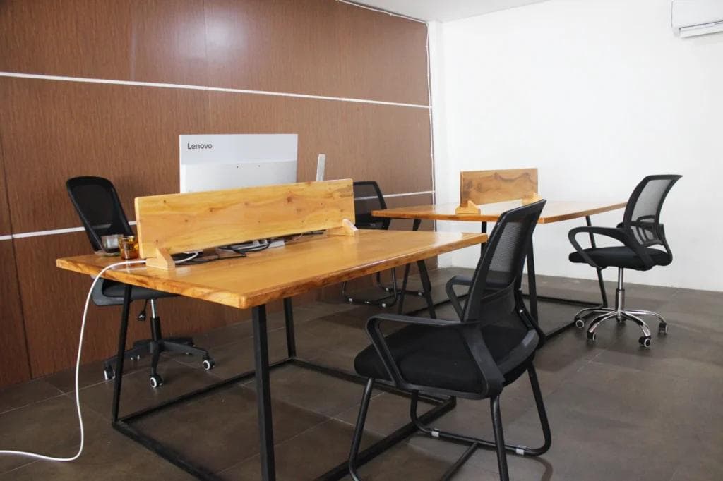 Interior coworking space dengan meja kayu dan area kerja bersama